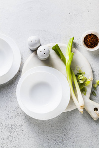 桌子上有空的白色盘子，用来煮汤和洋葱。 健康的厨房