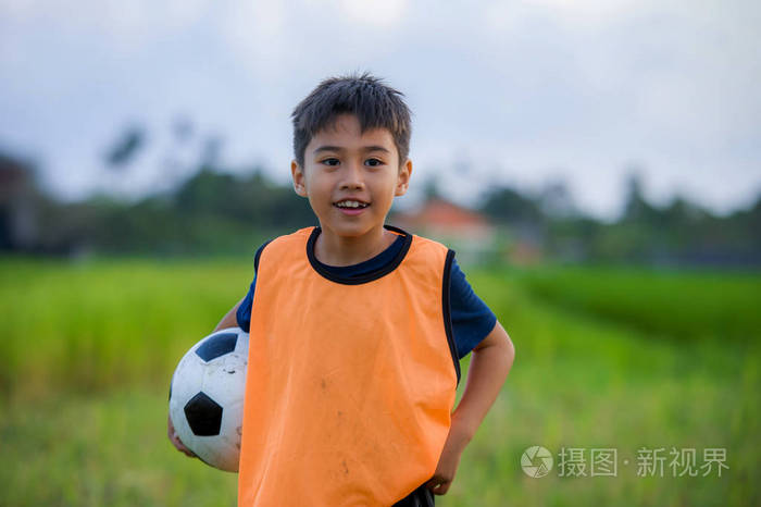 生活方式肖像英俊快乐的小男孩在绿草地户外踢球微笑着欢快地穿着训练