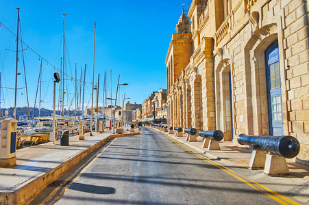 老式大炮沿着XattIlForn长廊的海洋博物馆墙，面对Vittoriosa码头与游艇和船只，伯古，马耳他。