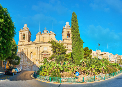 全景与美丽的景观花园自由纪念碑与仙人掌植物和高大的柏树后面，位于纪念碑圣劳伦斯教堂与巨大的钟楼比尔古Vittoriosa马耳