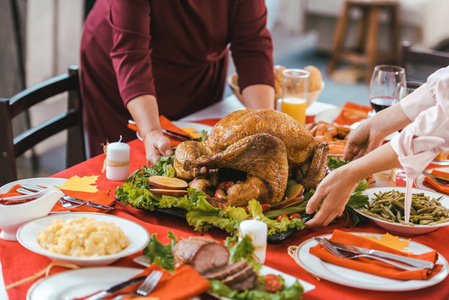 在感恩节桌上端着火鸡的盘子的女人