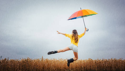 雨中的女人跳着五颜六色的雨伞图片