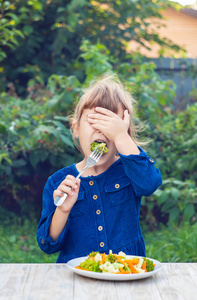 孩子吃蔬菜。 夏季照片。 选择性聚焦