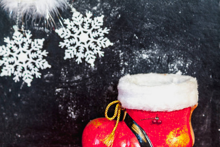 冬天还活着。 红色圣诞老人靴子和美丽的白色雪花在黑暗的背景上。