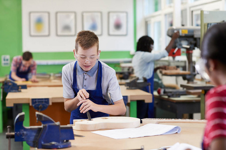 男子高中学生建筑吉他在木工课