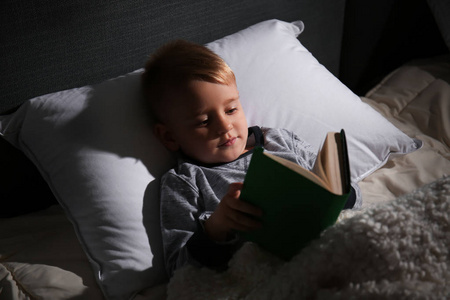 可爱的小男孩在床上看书