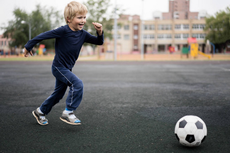 现代城市的积极生活方式在体育场里玩足球的小男孩