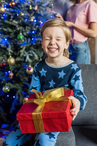 穿着睡衣的快乐小男孩拿着圣诞礼物