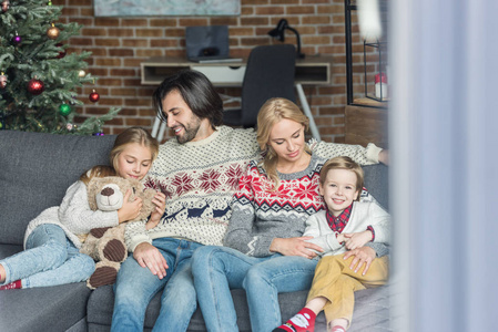 圣诞节的时候，幸福的家庭和两个孩子坐在沙发上