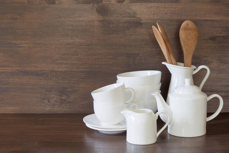 陶器，瓷器，白色器皿和其他不同的东西在木制台面上。 厨房仍然生活作为设计的背景。 复制空间。