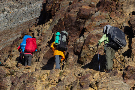 一群人徒步徒步旅行者背背包的一群人,男人和女人带着大袋子,上面附有