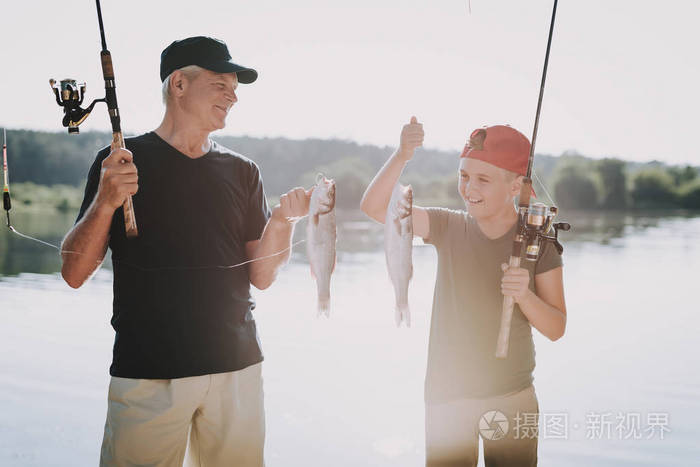 和祖父在湖里钓鱼的小孩. 钓着鱼竿的鱼既开心又兴奋库存照片. 图片包括