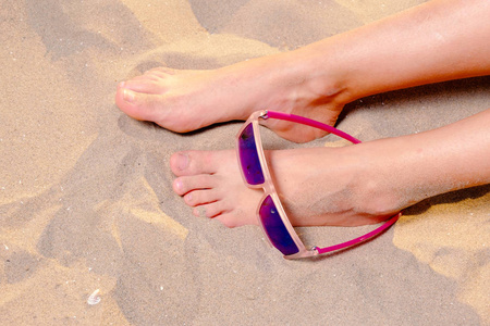 裸脚女孩与太阳镜在她的脚以上的看法之一照片