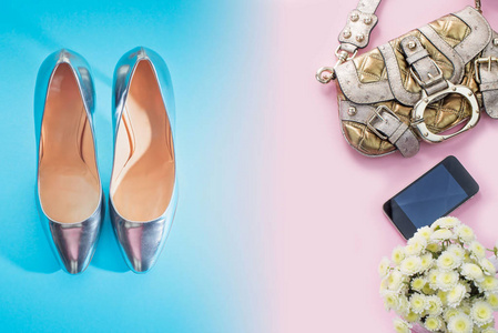 现代时尚配饰年轻女鞋，手袋，鞋，银梯度，蓝色花束，粉红色背景。 俯视图平躺