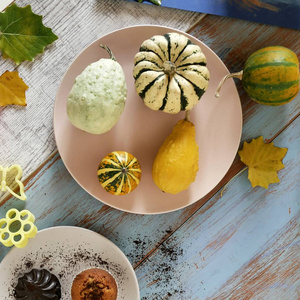 秋天的南瓜组成不同品种的纸杯蛋糕，梨，饼干形状，为节日准备甜点，在浅色的木制背景下，万圣节的顶部视图。