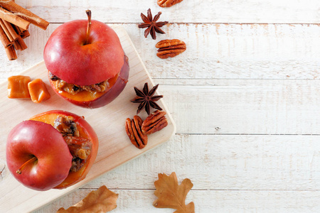 用焦糖红糖和坚果烤苹果. 顶部视图边框在白色木材背景与复制空间.