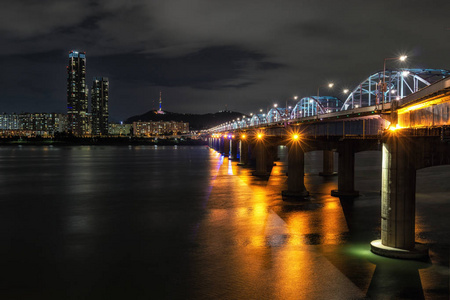 东贾克桥越过汉江和著名的地标南三塔在远处拍摄的夜晚。韩国首尔