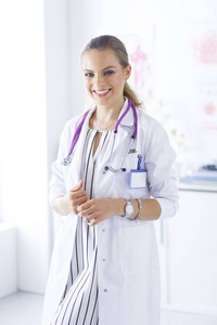 微笑的女医生与一个医疗听诊器在制服站立