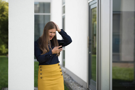 年轻的商务女性，在办公楼前拿着智能手机，解决问题