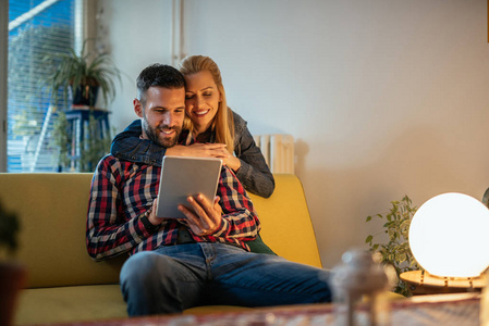吸引人的年轻夫妇在他们的数字平板电脑上从家里上网。