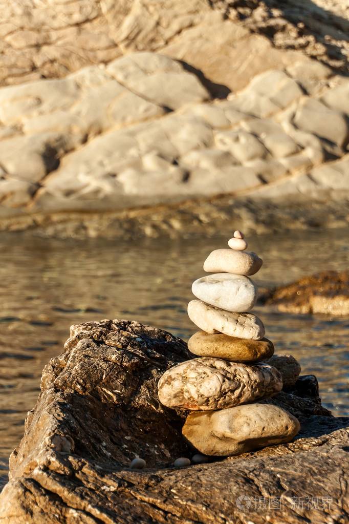 海边的卵石堆.海滩上的石头金字塔.日落时分的光线.耐心的象征.