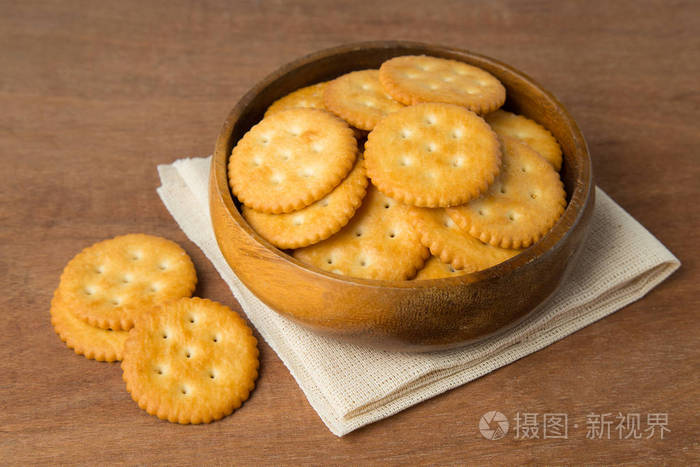 圆形咸饼干在木制碗放在亚麻和木制背景