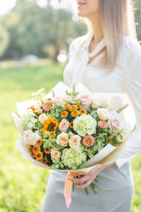 小姑娘捧着鲜花安排各种颜色.明亮的黎明或日落的太阳照片