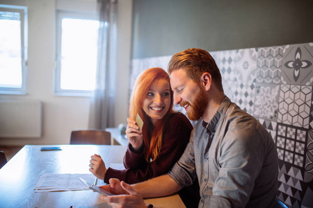 幸福的年轻夫妇在家里通过数字平板电脑在线购物的肖像。