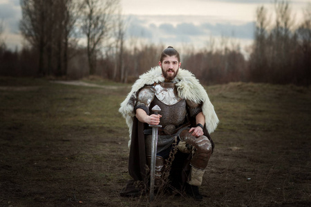 身穿盔甲的骑士,手里拿着剑,单膝站立.摄影图