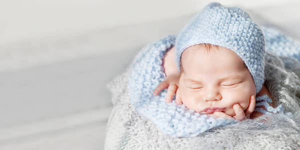 可爱的新生婴儿睡觉。新生男孩把手叠在篮子里。关闭图像。复制空间
