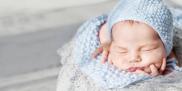 可爱的新生婴儿睡觉。新生男孩把手叠在篮子里。关闭图像。复制空间