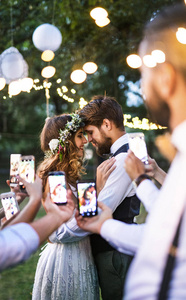 客人与智能手机拍照新娘和新郎在婚礼招待会外