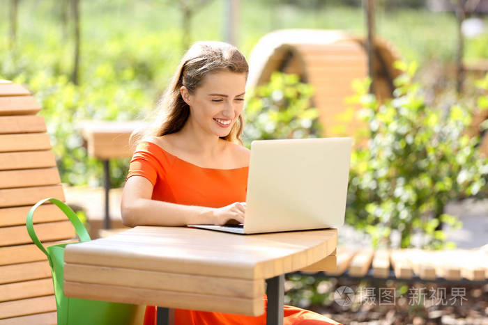 漂亮的年轻女人在户外使用笔记本电脑