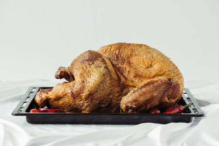 在烤盘上，在灰色背景上铺上桌布，在感恩节假日晚餐的概念上，近距离观看煮熟的节日火鸡。