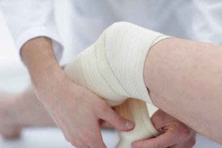 手的特写女人用绷带包扎女腿特写护士和医生外科医生包扎病人术后腿脚