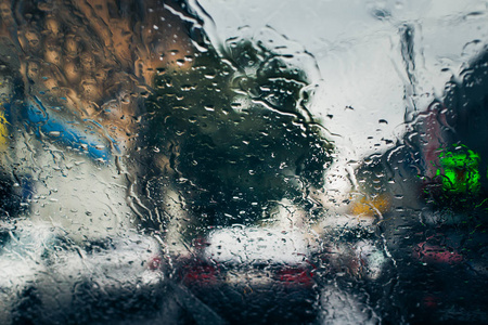 在汽车挡风玻璃上看到雨水滴落的城市道路