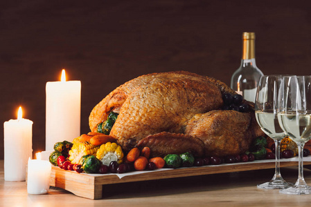 在木制桌面上观看传统烤火鸡蔬菜和一杯葡萄酒作为感恩节晚餐