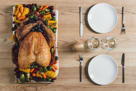 在桌面上放着烤火鸡蔬菜和一杯葡萄酒作为感恩节假日晚餐