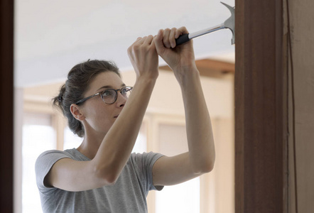 用锤子在家修理门的女人家庭装修和DIY概念