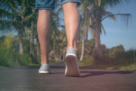 s legs while walking through a street with palm  trees.