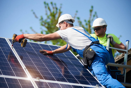 两名工人技术人员将重型太阳能照片Voltaic面板连接到高钢平台上。 外部太阳能系统安装替代可再生绿色能源发电理念。