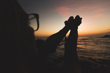 祈祷女孩的手在日落日出与海海洋背面。