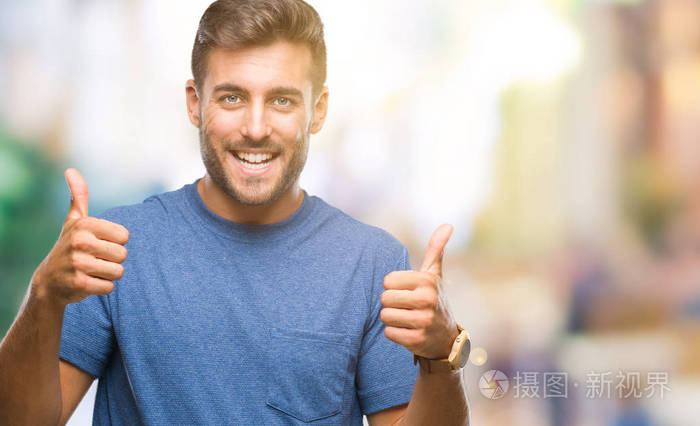 年轻英俊的男人越过孤立的背景成功标志,做积极的手势,用手竖起大拇指