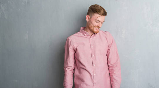 年轻的红头发男人穿着粉红色的衬衫，脸上带着微笑，自然的表情。 自信地笑着。