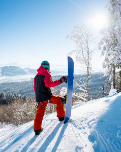 全长镜头的一个男性滑雪板站在一个斜坡上，他的滑雪板环顾四周，享受视野，共空间，冬季山脉，景观，生活方式的概念。