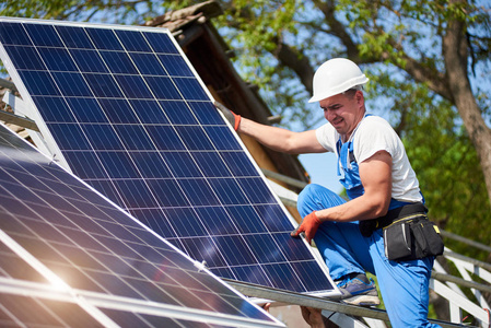 专业技术人员在蓝天和绿树背景下将重型太阳能照片Voltaic面板安装到高金属平台上。 独立太阳能系统安装绿色能源生产理念。