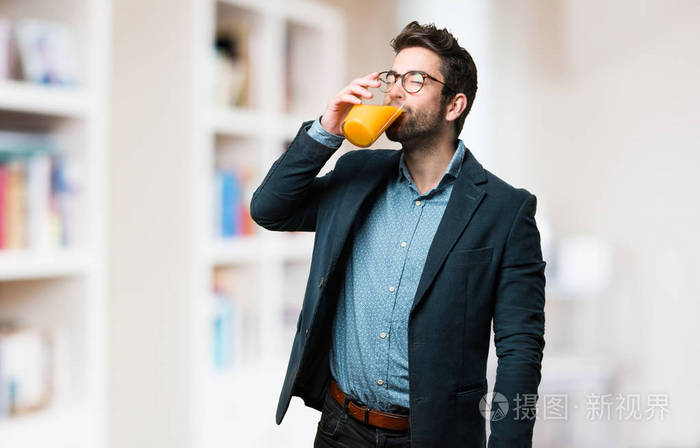 在模糊的背景下喝果汁的年轻人