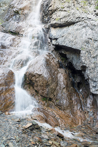 高山瀑布在阿尔泰共和国俄罗斯的大岩石中闪闪发光。 大石岩轻水瀑布美丽的瀑布
