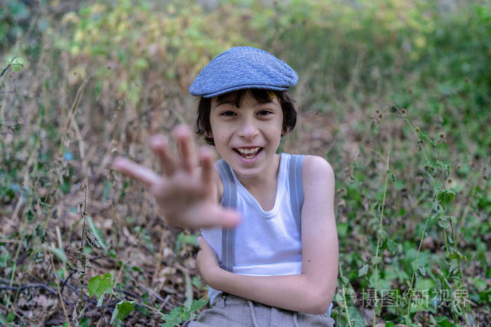 一个穿无袖衬衫和吊带的快乐男孩伸出手向前.