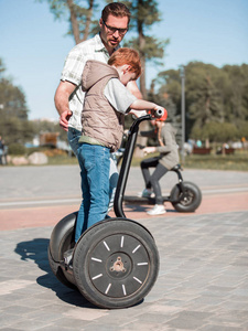 父亲教儿子在公园里骑迷你 hoverboard。